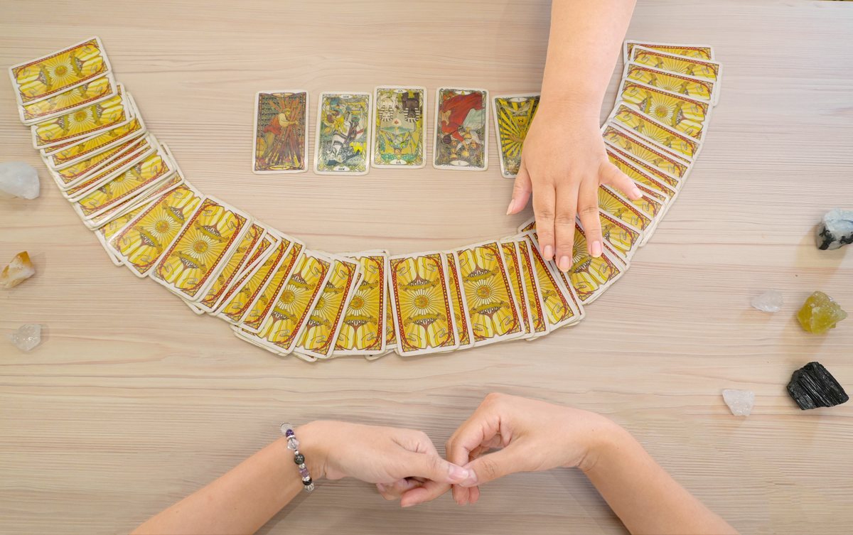 贈品專業塔羅牌乙副：金色牌背的塔羅牌在淺木紋桌面上扇形攤開，上方一排翻開五張正面牌